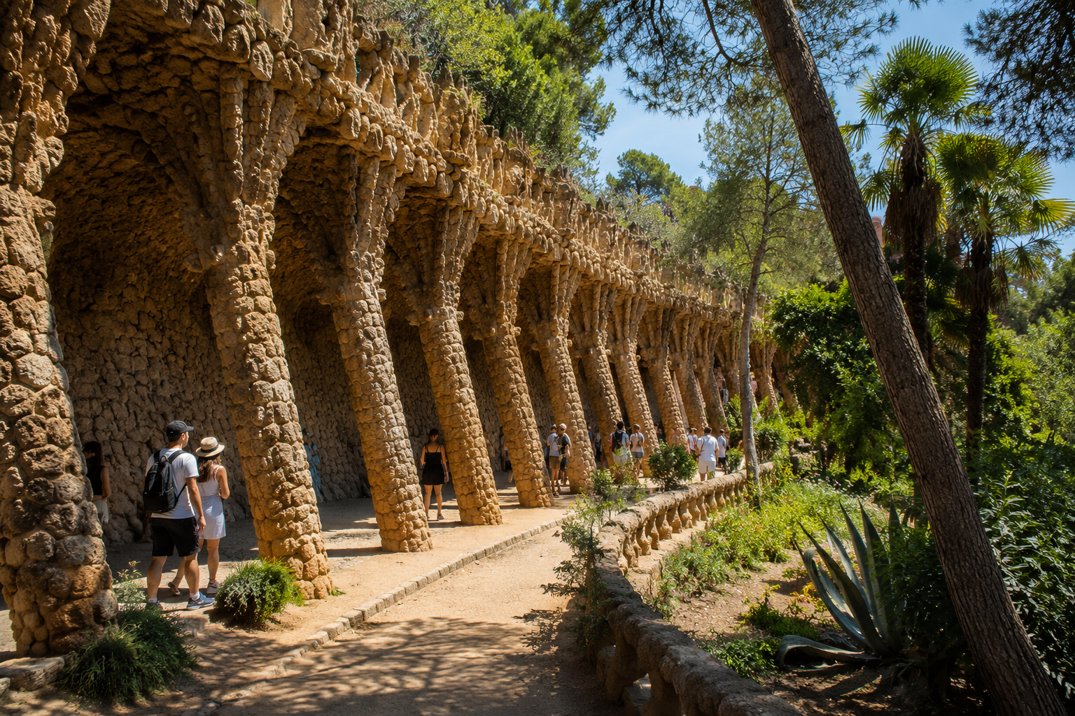 Gaudí’s Laundry Room Portico at Park Güell in Barcelona with leaning stone columns surrounded by trees and gardens