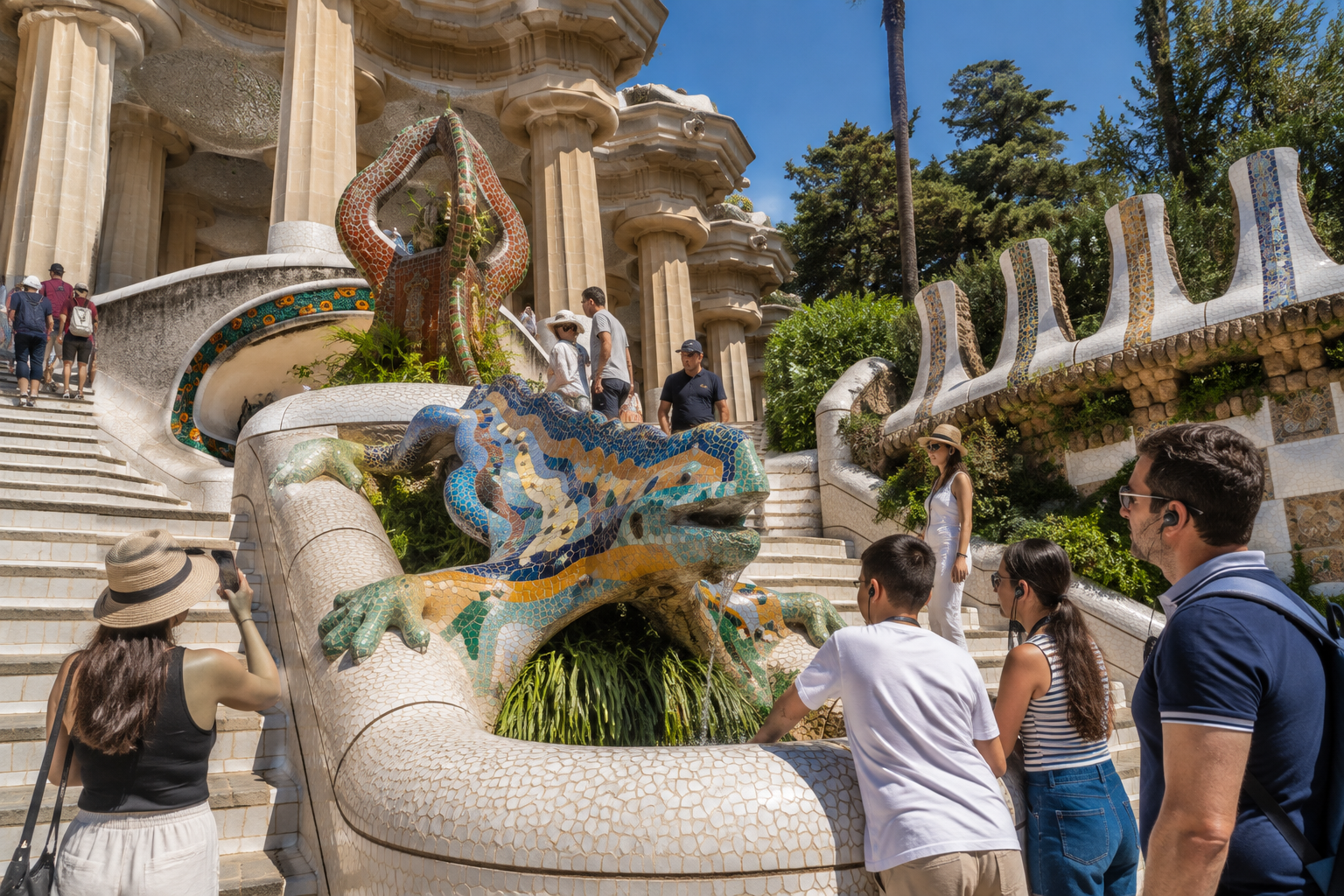 El Drac mosaic salamander on the Dragon Stairway at Park Güell in Barcelona with visitors exploring Gaudí’s architecture